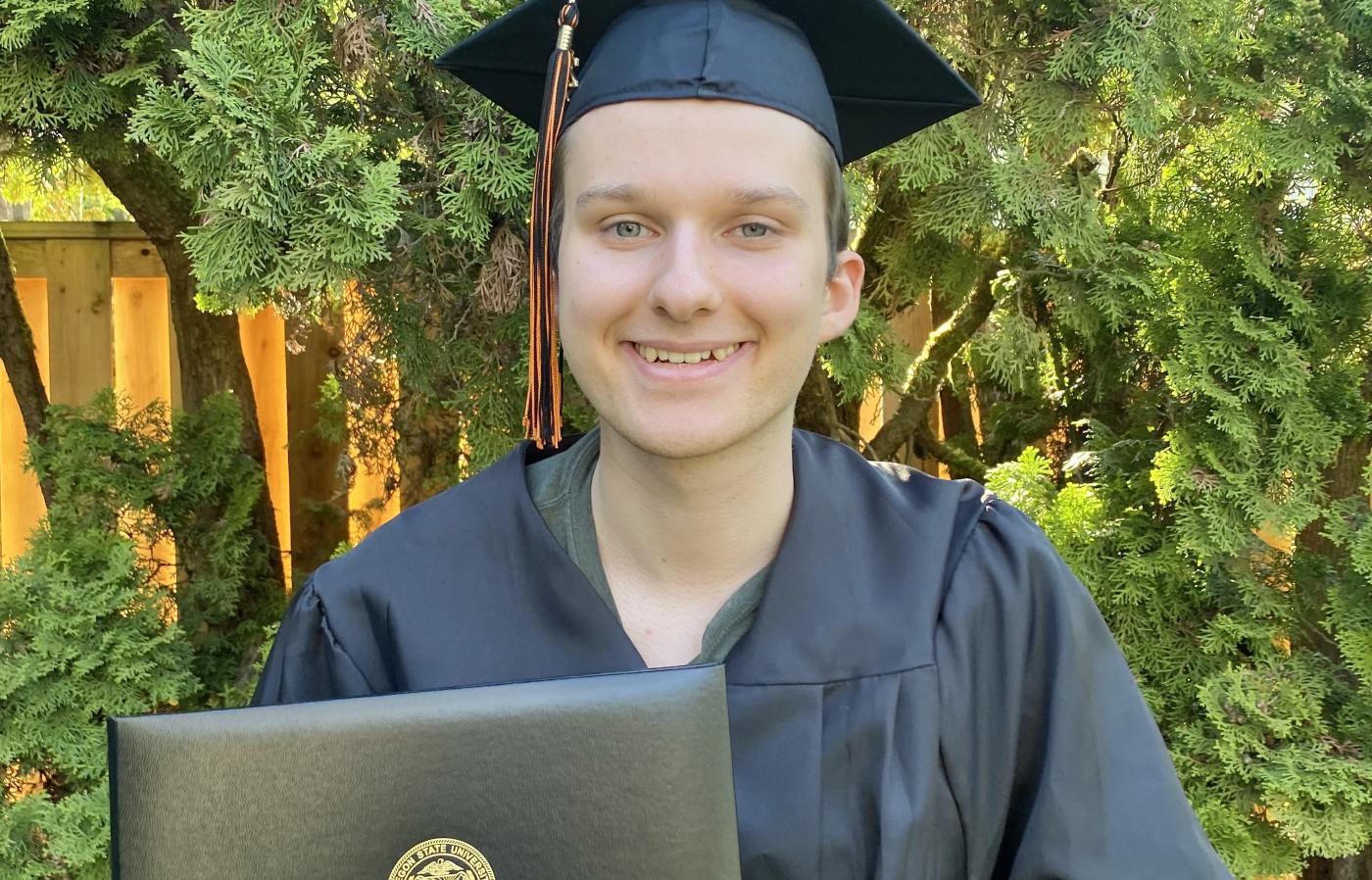 Person smiling wearing graduation cap and gown.